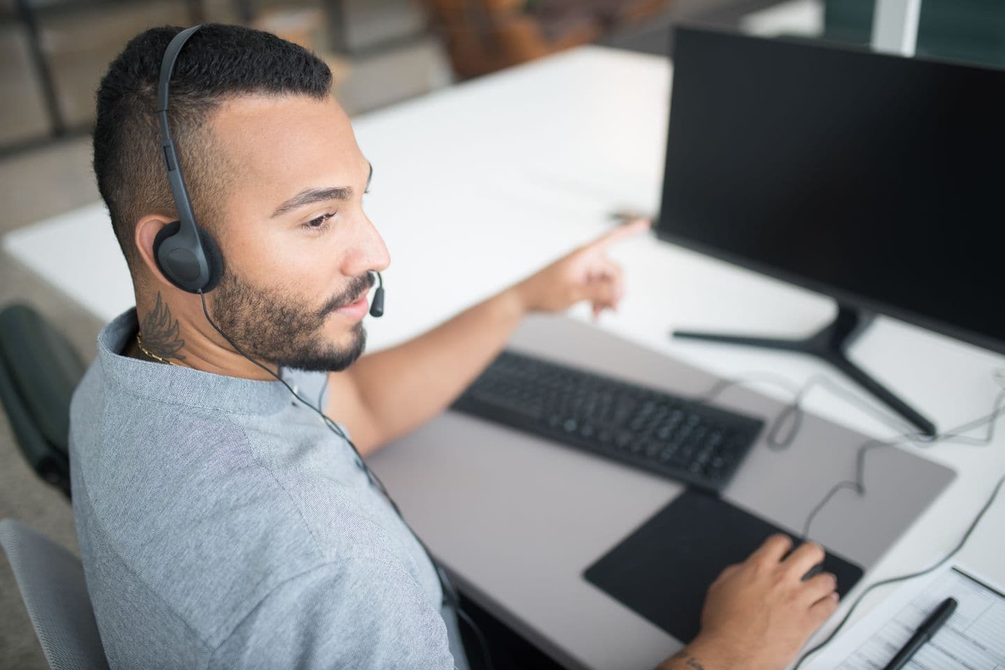 Contact centre agent at a workstation wearing a headset, in the kind of environment where AI voice agents now handle the front of the call