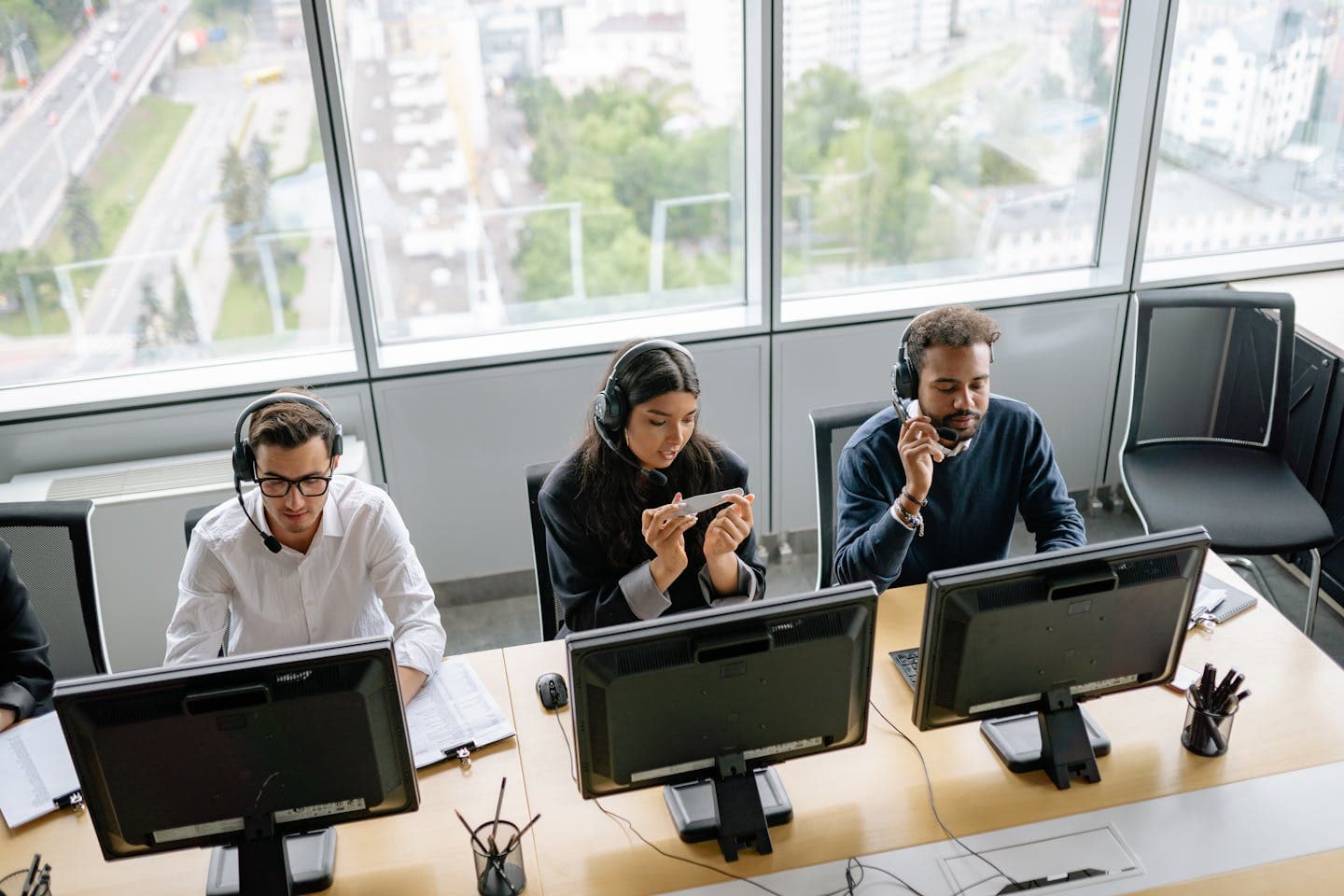Contact-centre team working at a row of desks in a modern office, headsets on, handling customer calls.