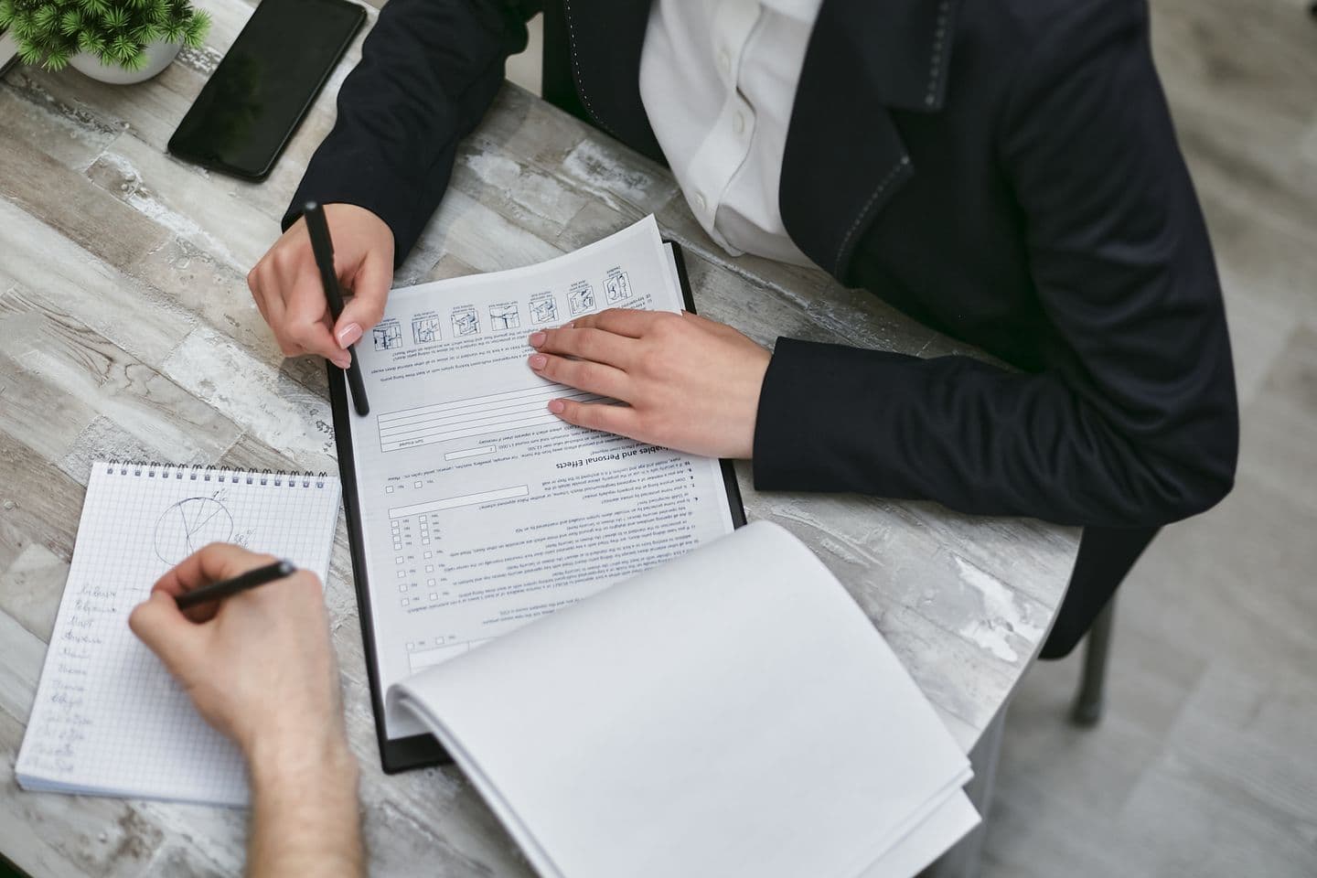 Two colleagues working through compliance paperwork at an office desk, the evidence-gathering stage of a PCI self-assessment