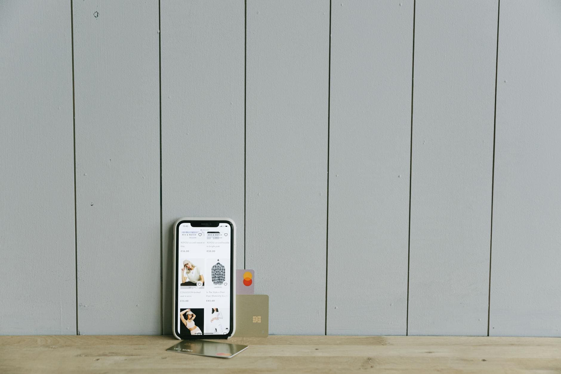 A smartphone displaying an ecommerce site with a credit card, set on a wooden surface, depicting onl