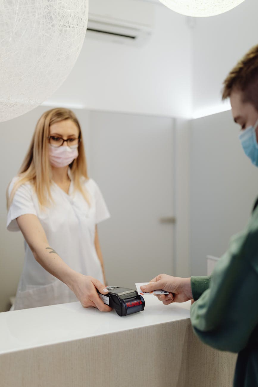 Patient making a card payment at a healthcare clinic counter using a card terminal