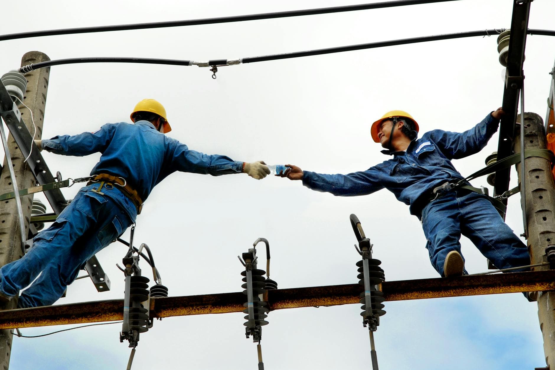 Electrical workers in blue uniforms maintaining overhead power lines
