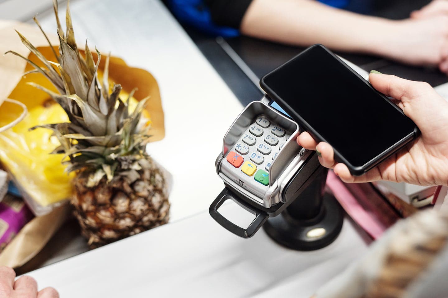 Close-up of a customer using a smartphone for contactless payment at a retail checkout.