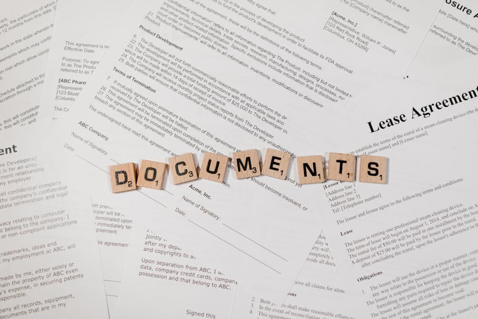 Top view of scrabble tiles spelling 'DOCUMENTS' on various contracts and agreements.