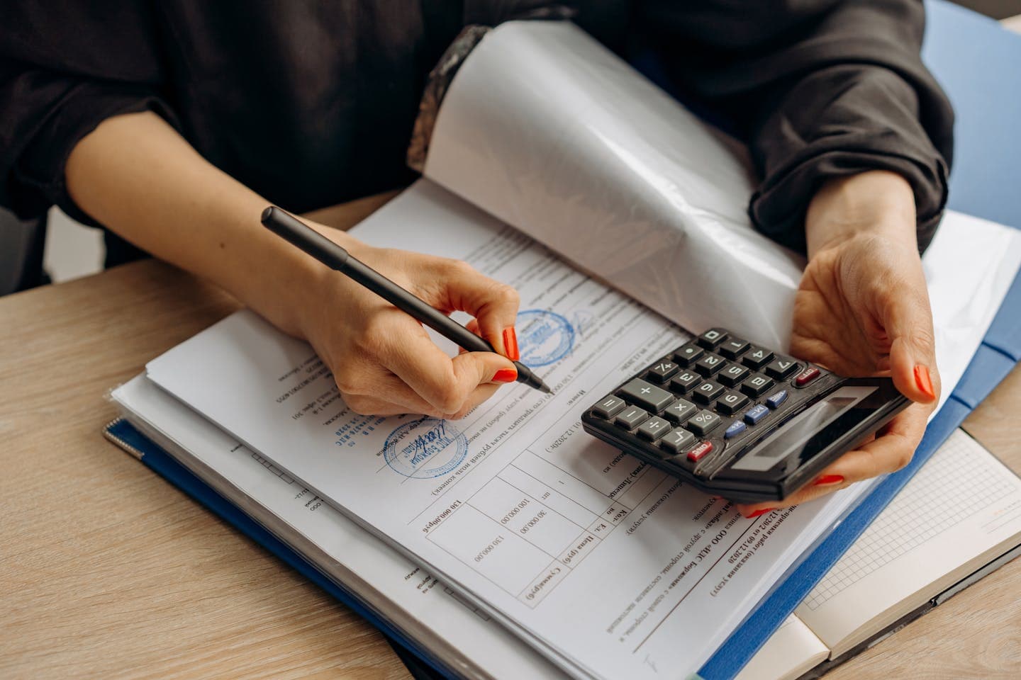 An accountant using a calculator and signing paperwork, showcasing financial analysis.