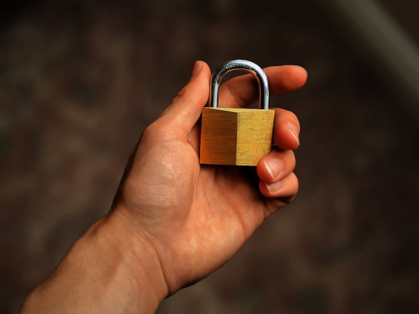 Hand holding a brass padlock, symbolizing security and protection
