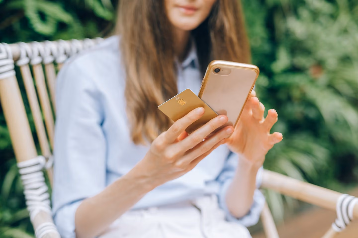 A woman making an online purchase using a smartphone and credit card outdoors.