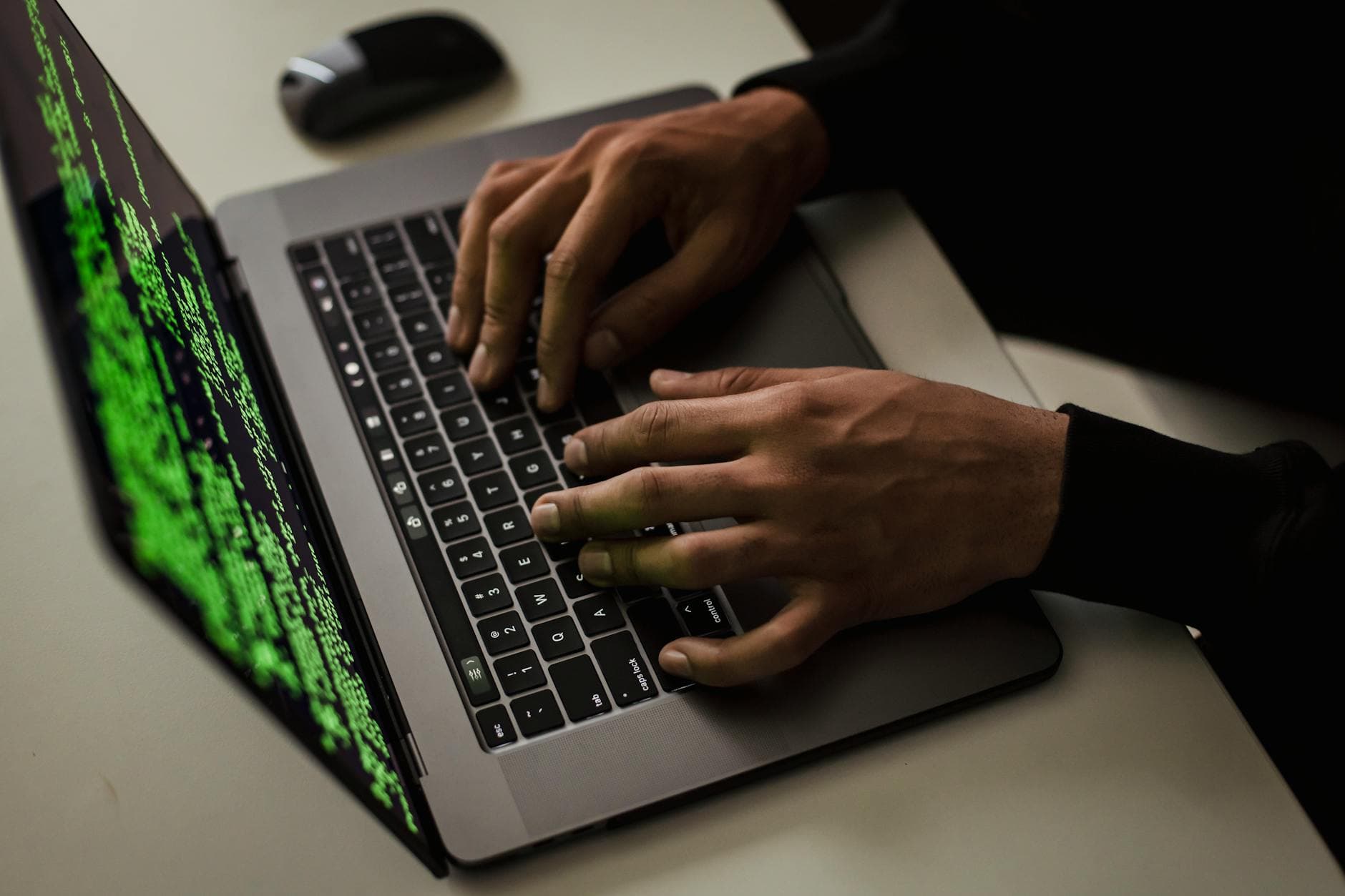 Overhead view of an anonymous figure typing on a small laptop showing data on the screen