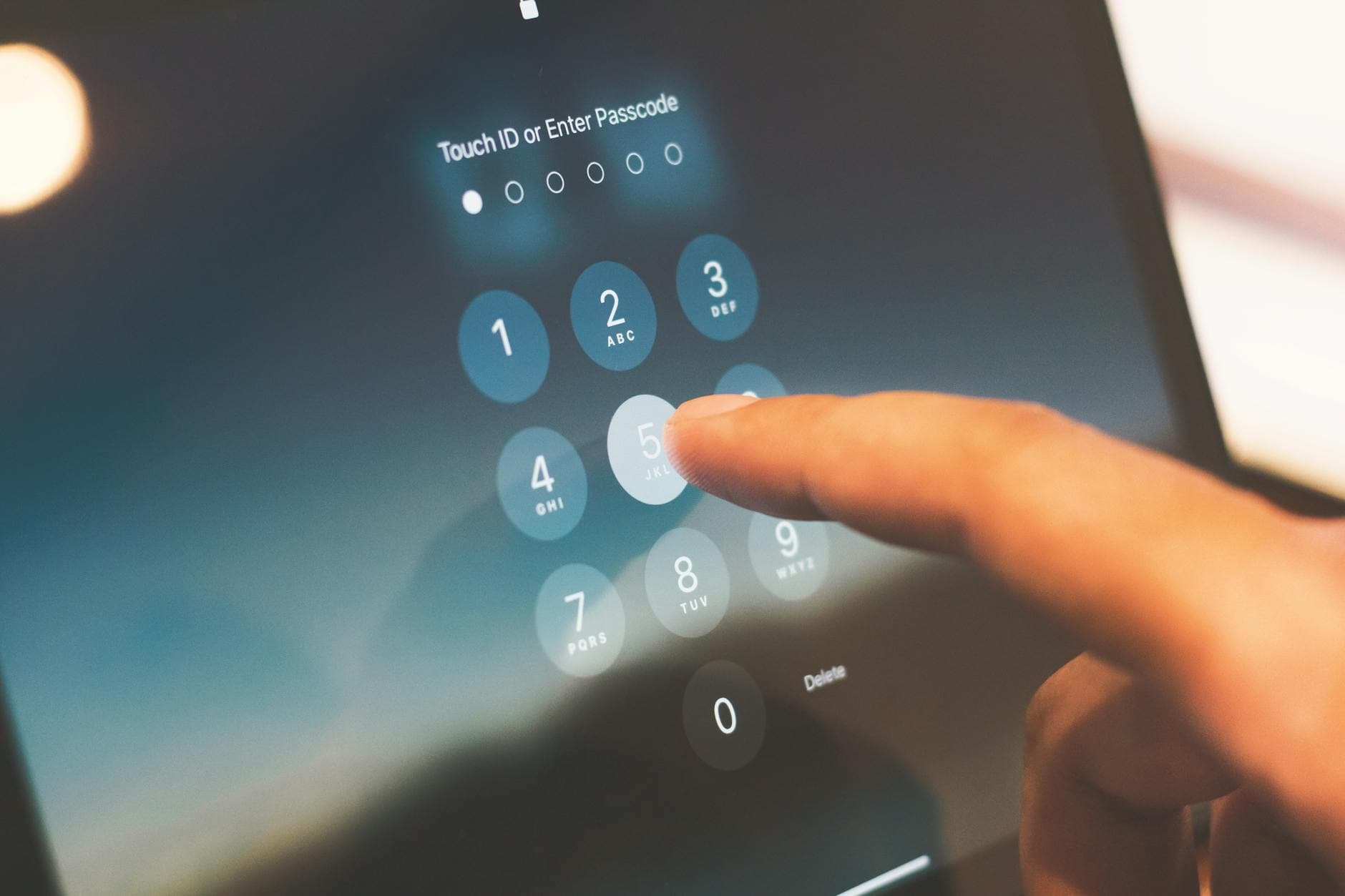 Close-up of a finger entering a passcode on a smartphone keypad screen