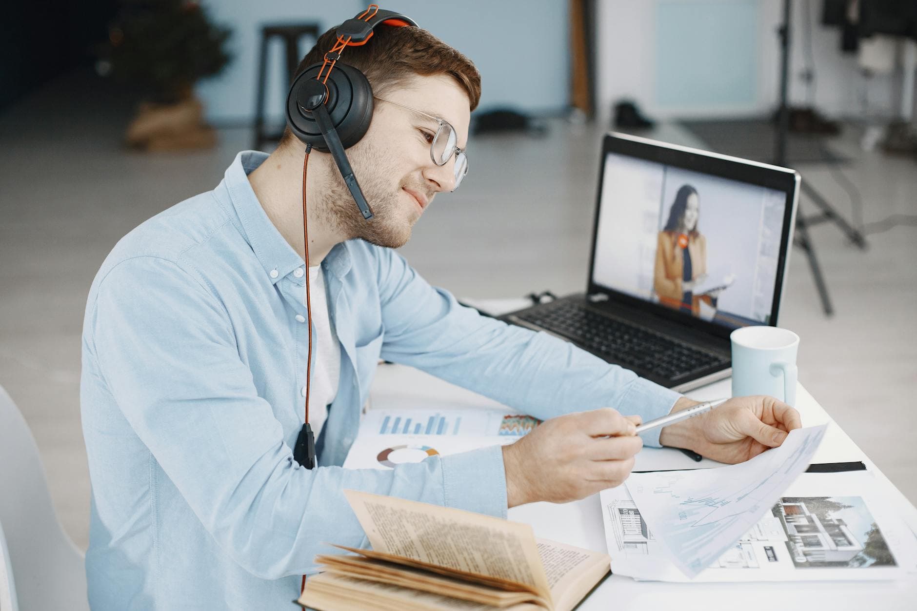 Man working remotely with headphones reviewing documents on a video call from a laptop