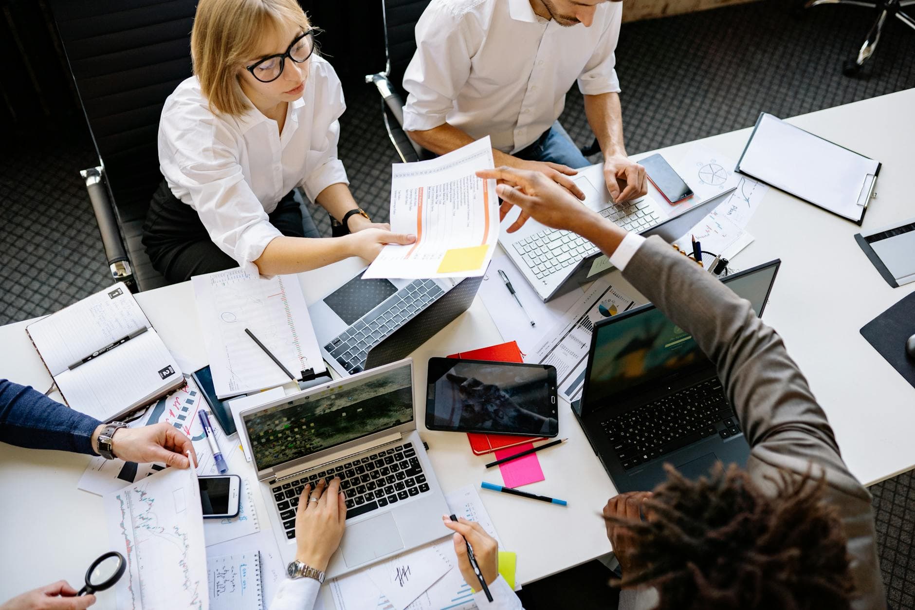 Diverse business team collaborating around laptops and documents in a modern office