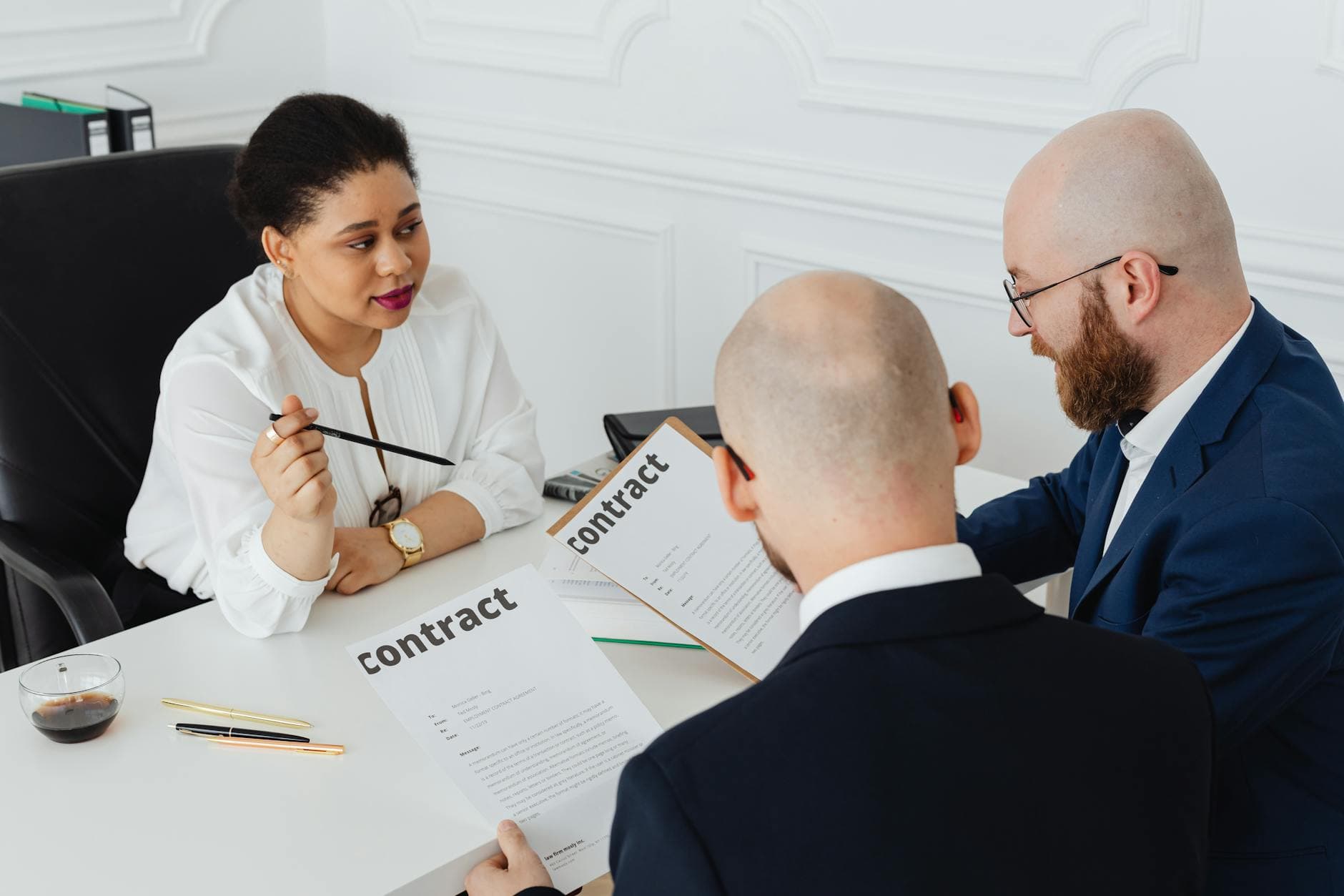 Three business professionals seated around a conference table discussing a contract document in a modern office