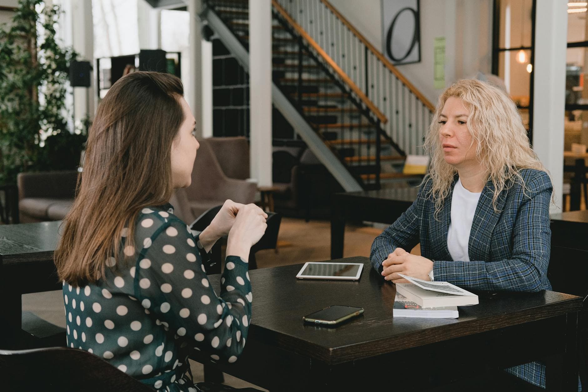 Two businesswomen seated at a table with a laptop and notebook having a focused vendor discussion