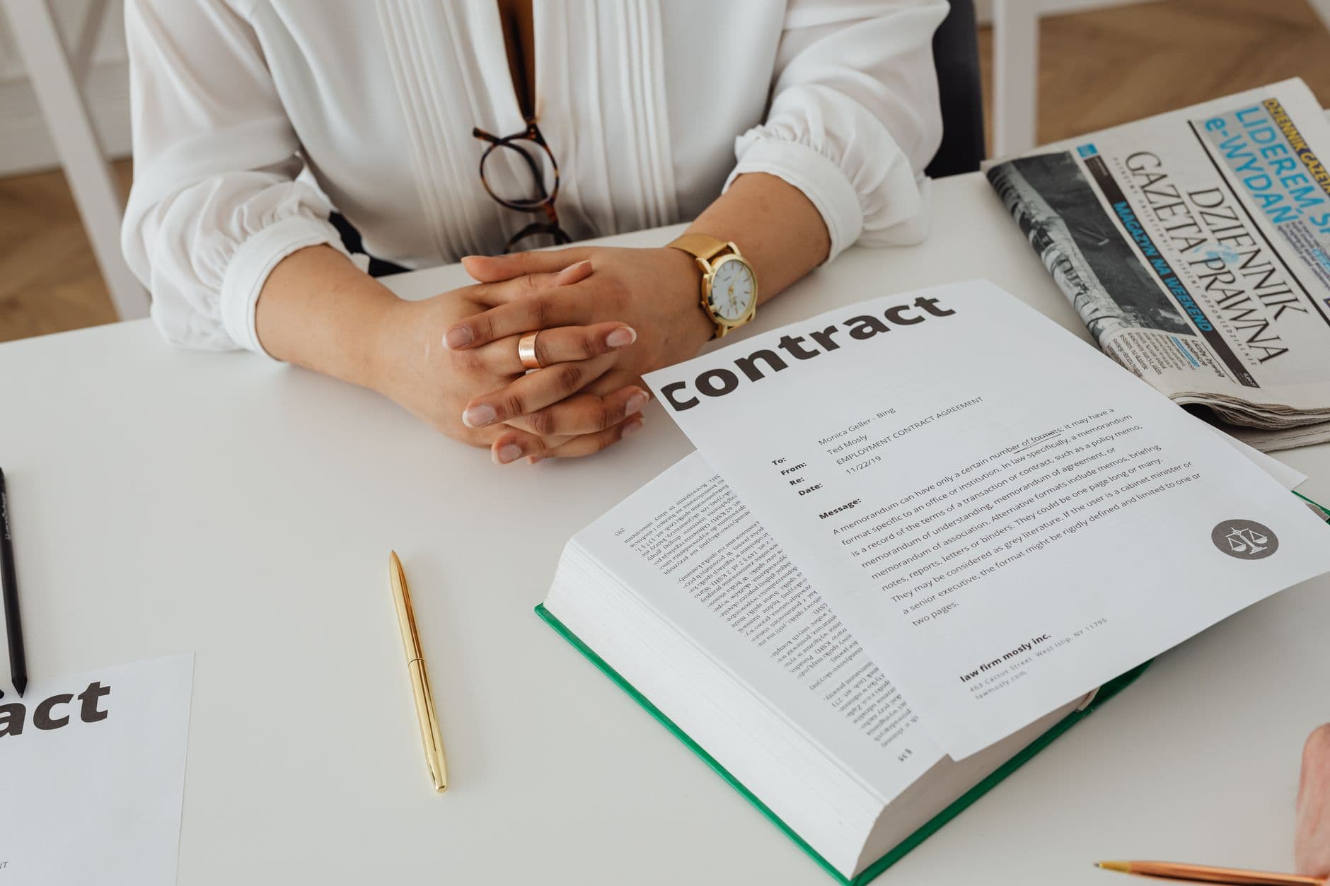 Businesswoman at a desk reviewing a printed contract with legal documents spread in front of her