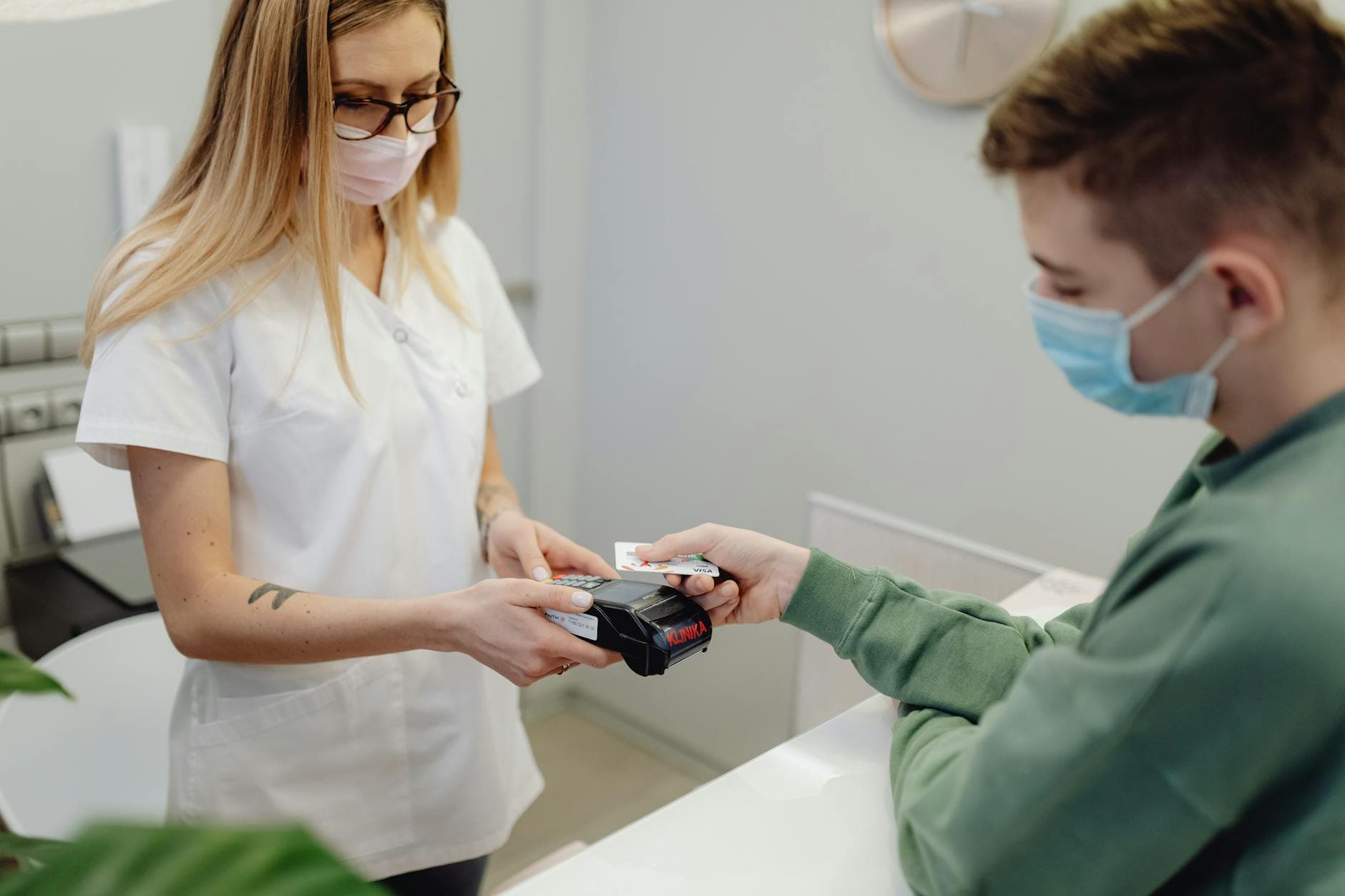Healthcare staff member processing a patient's credit card payment at a clinic reception counter