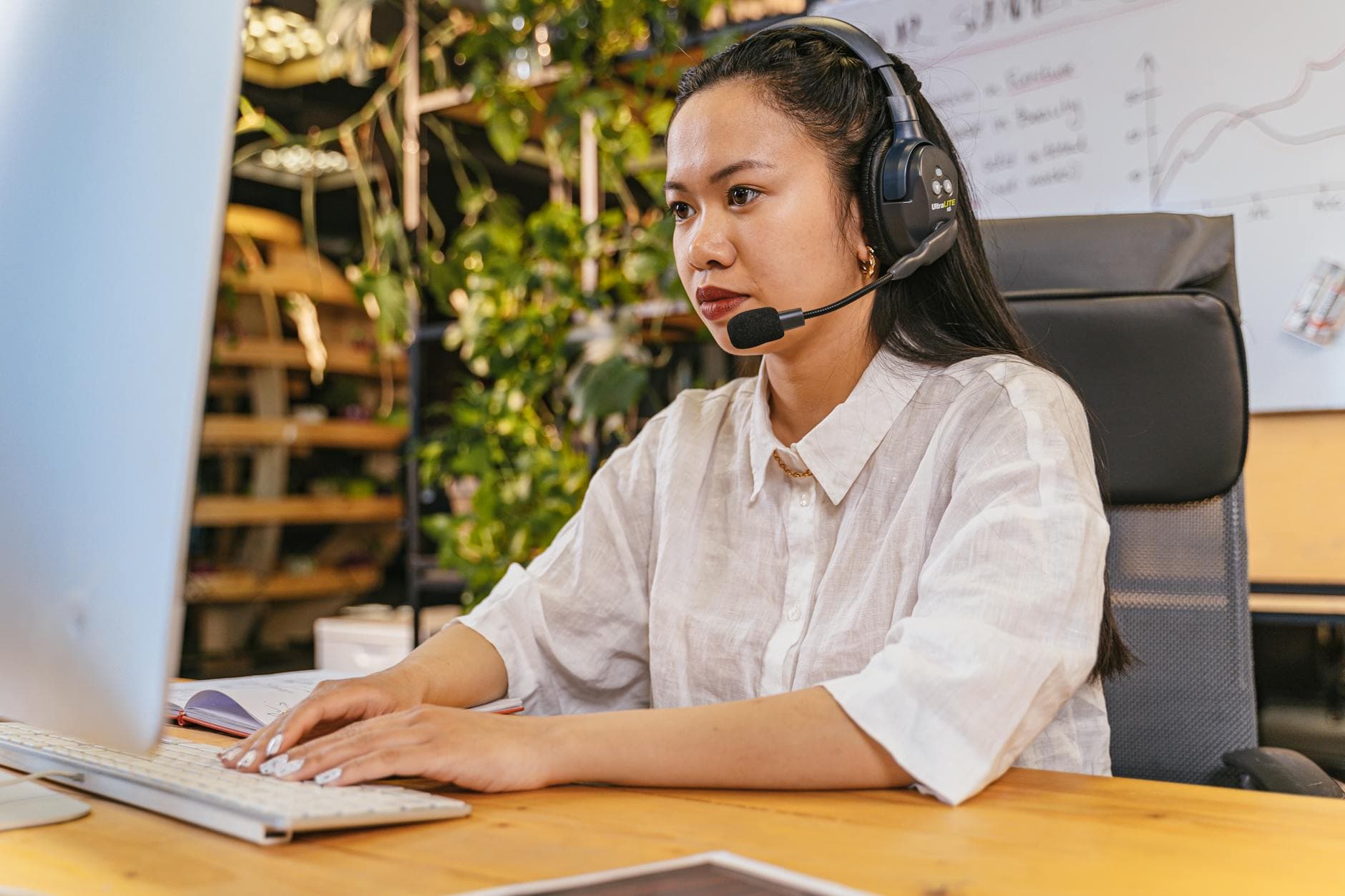 Professional woman working at a computer with a headset in a modern home office