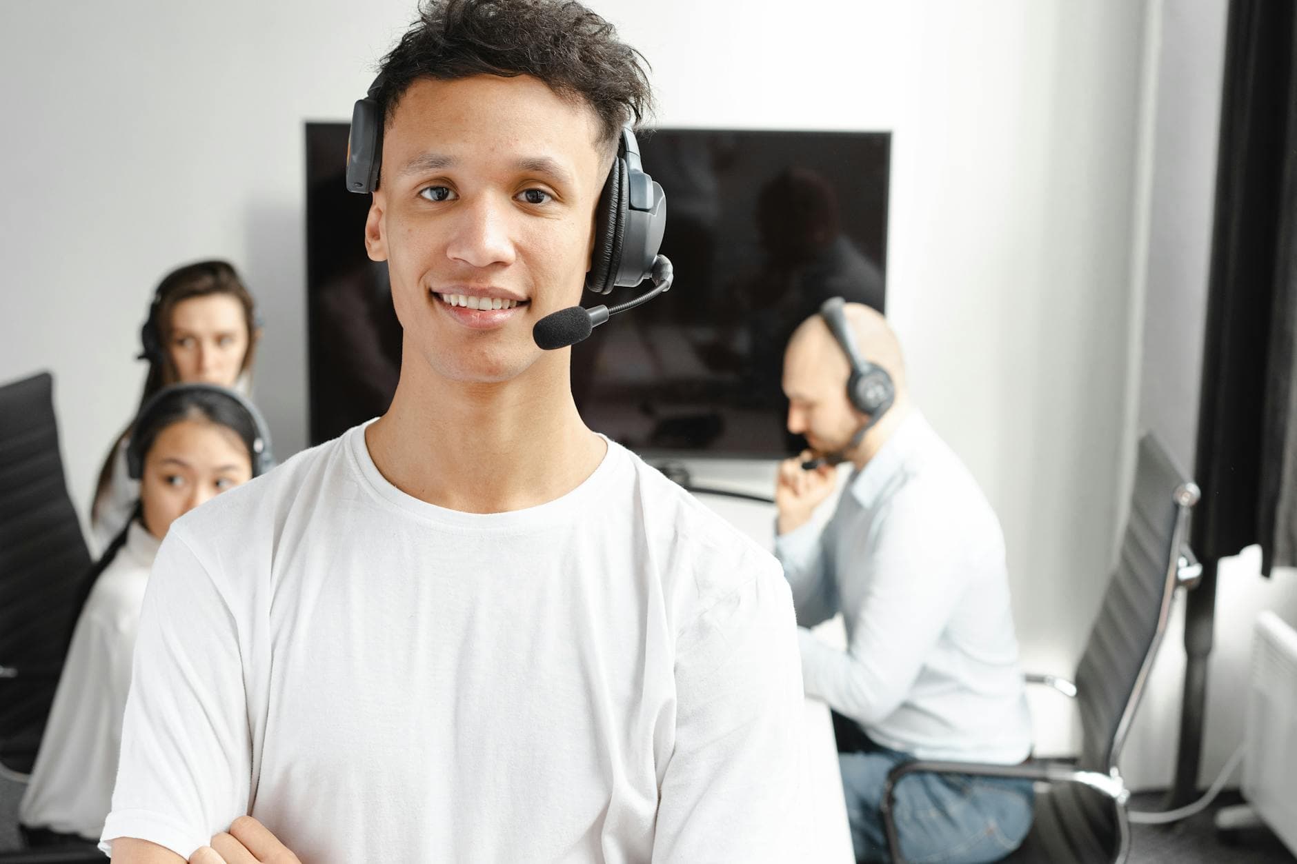 Smiling contact center agents wearing headsets in a bright modern office handling customer calls