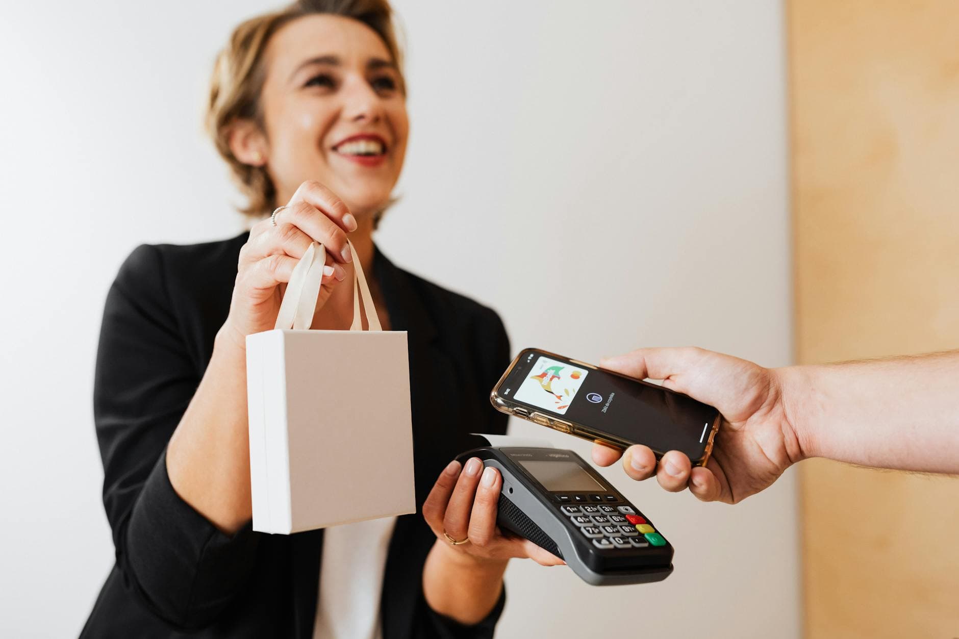 Cashier at a modern retail counter accepting a contactless mobile payment from a customer's smartphone