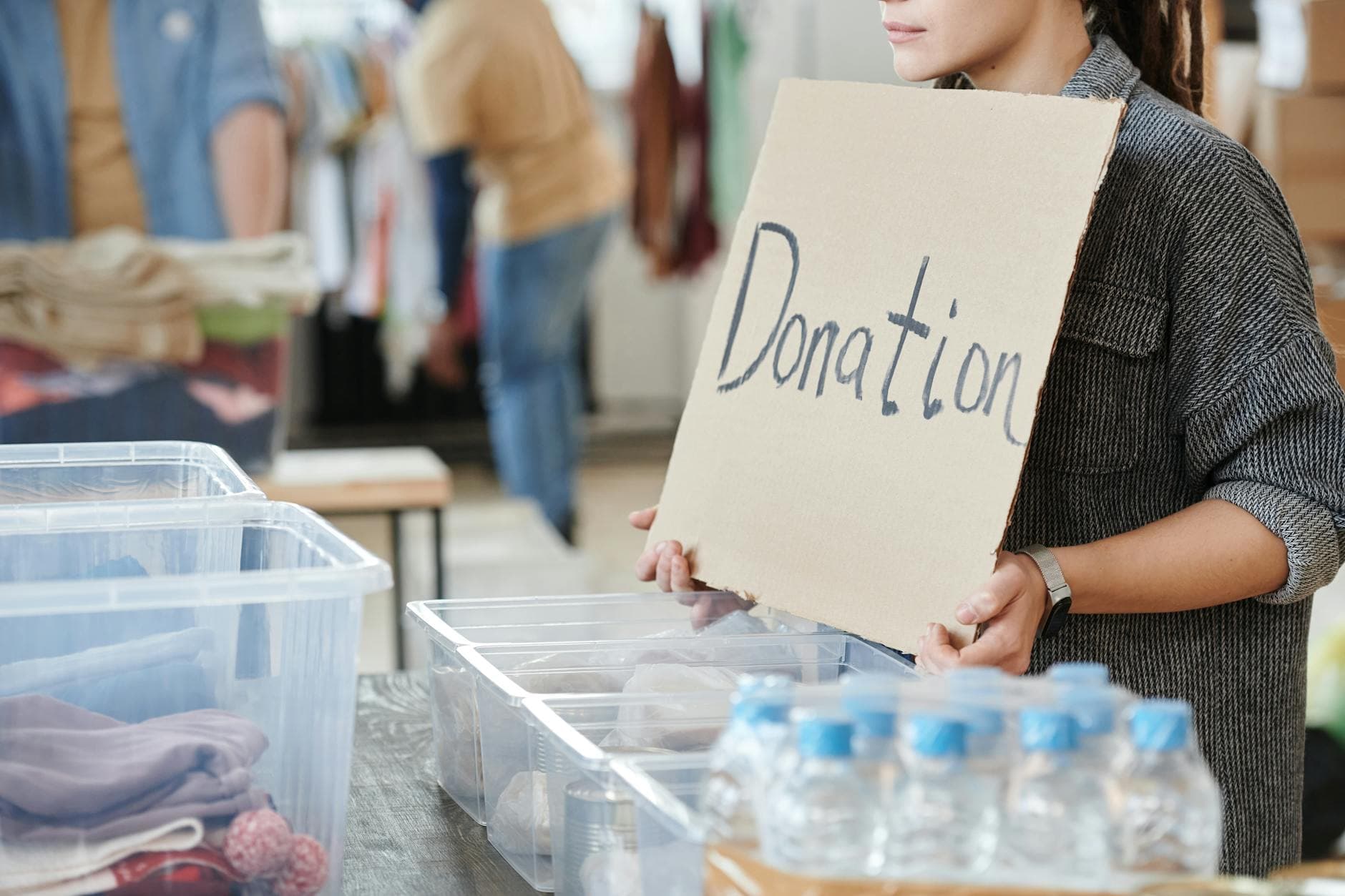 Charity volunteer holding a hand-written donation sign at a fundraising event