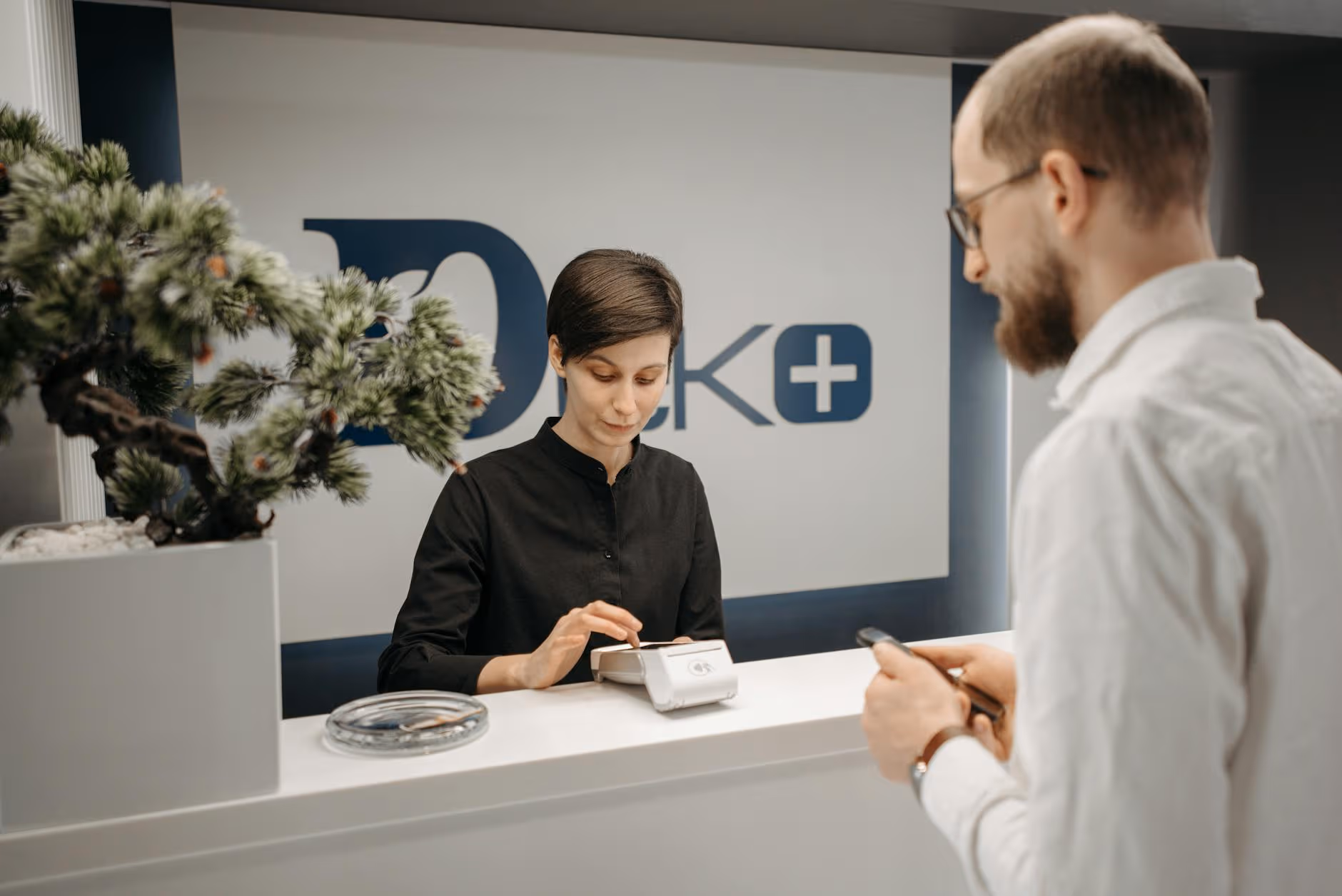 Patient making a cashless card payment at a medical clinic reception
