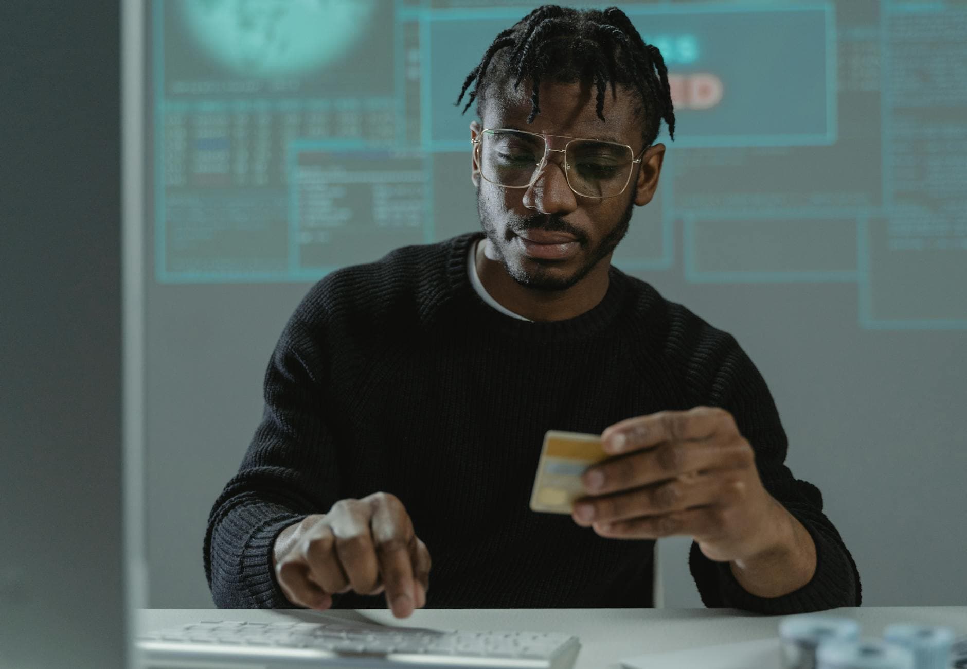 Hands holding a bank card while typing on a keyboard — card-not-present fraud prevention