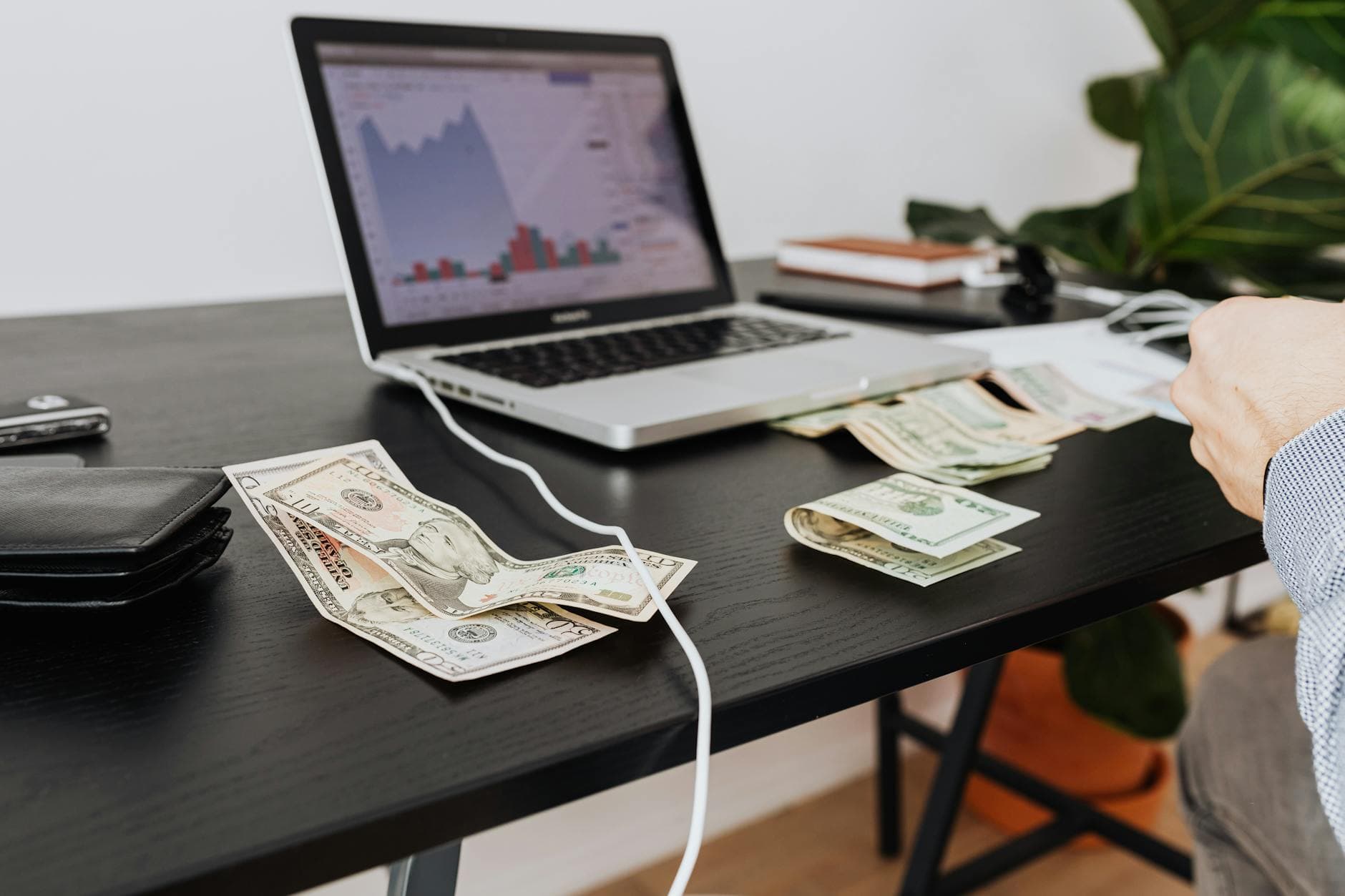 Workspace with cash, laptop, and financial analysis charts
