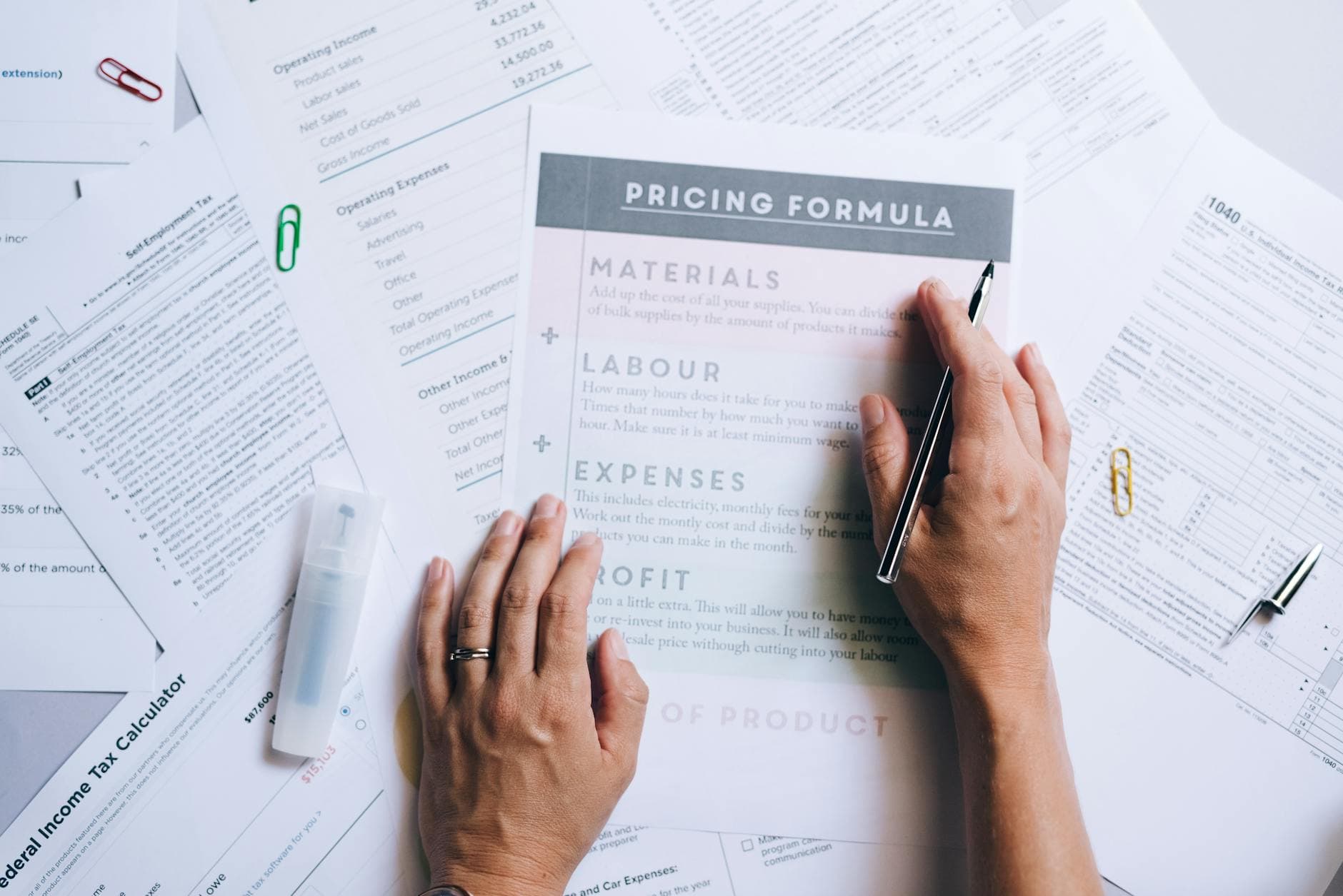Hands organising business documents and pricing papers on a desk