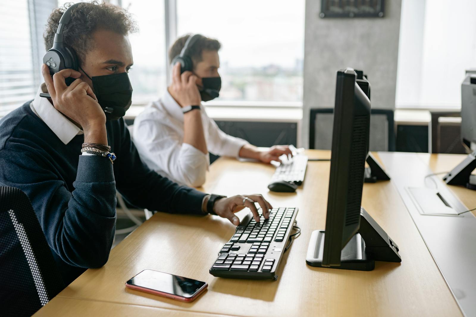 Contact centre agent wearing a headset working at a dual-monitor workstation during a customer call