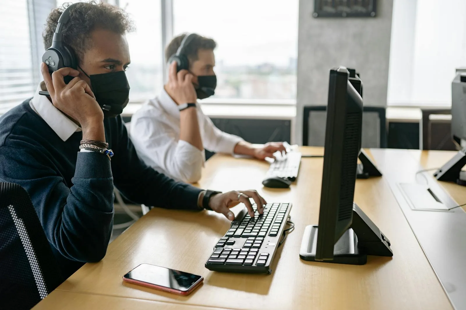 Contact centre agent wearing a headset working at a dual-monitor workstation during a customer call