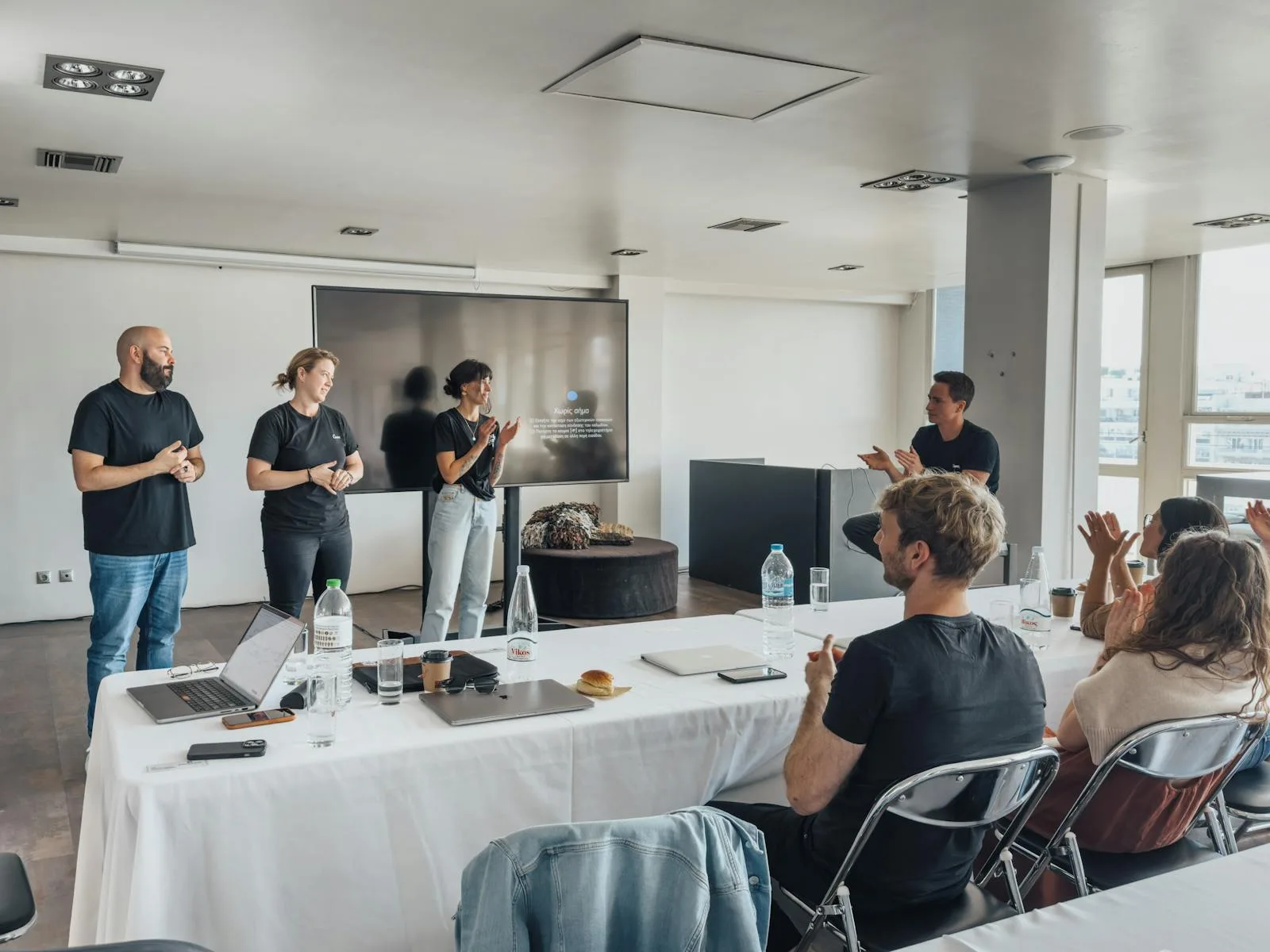 Employees gathered around laptops during an in-house staff training session in a modern office